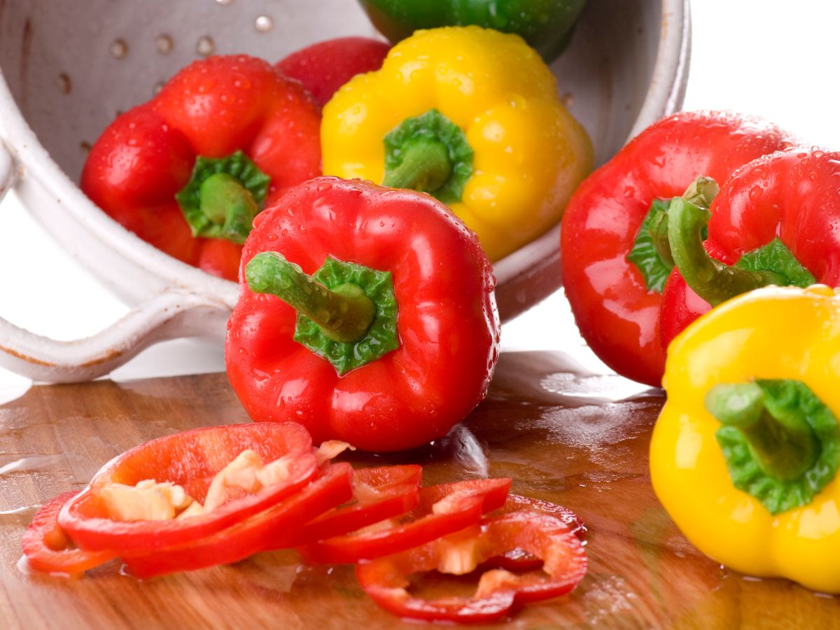 Bell peppers in a pot and on a wooden cutting board