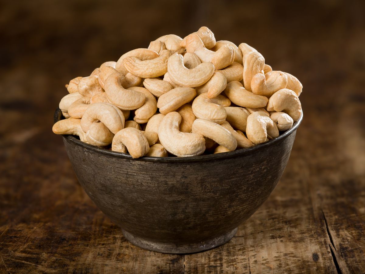 Brown bowl full of cashew nuts on a table.