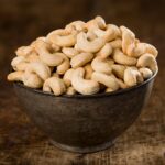 Brown bowl full of cashews in a table.