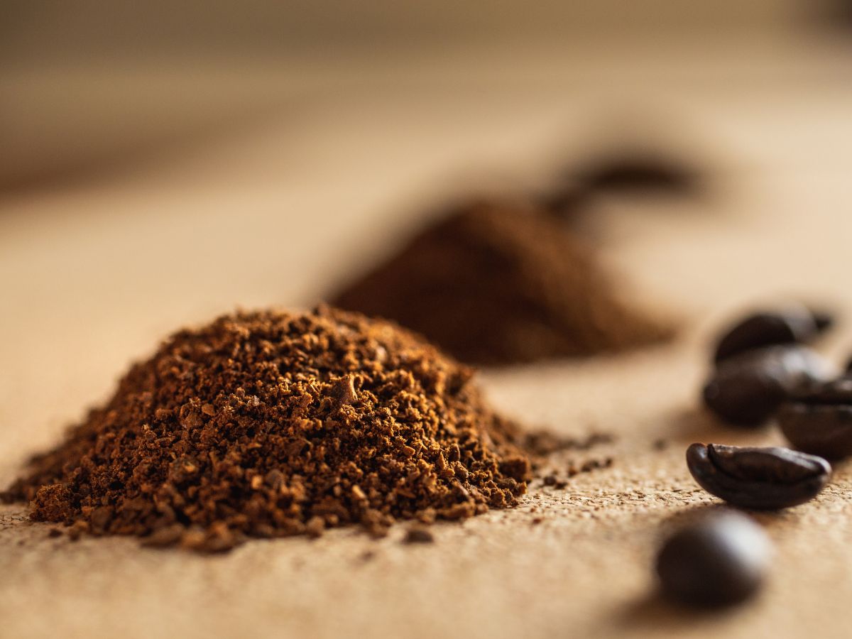 Pile of coffee grounds on a table with coffee beans.