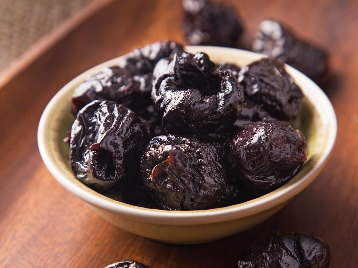 Bowl of prunes on a wooden table.