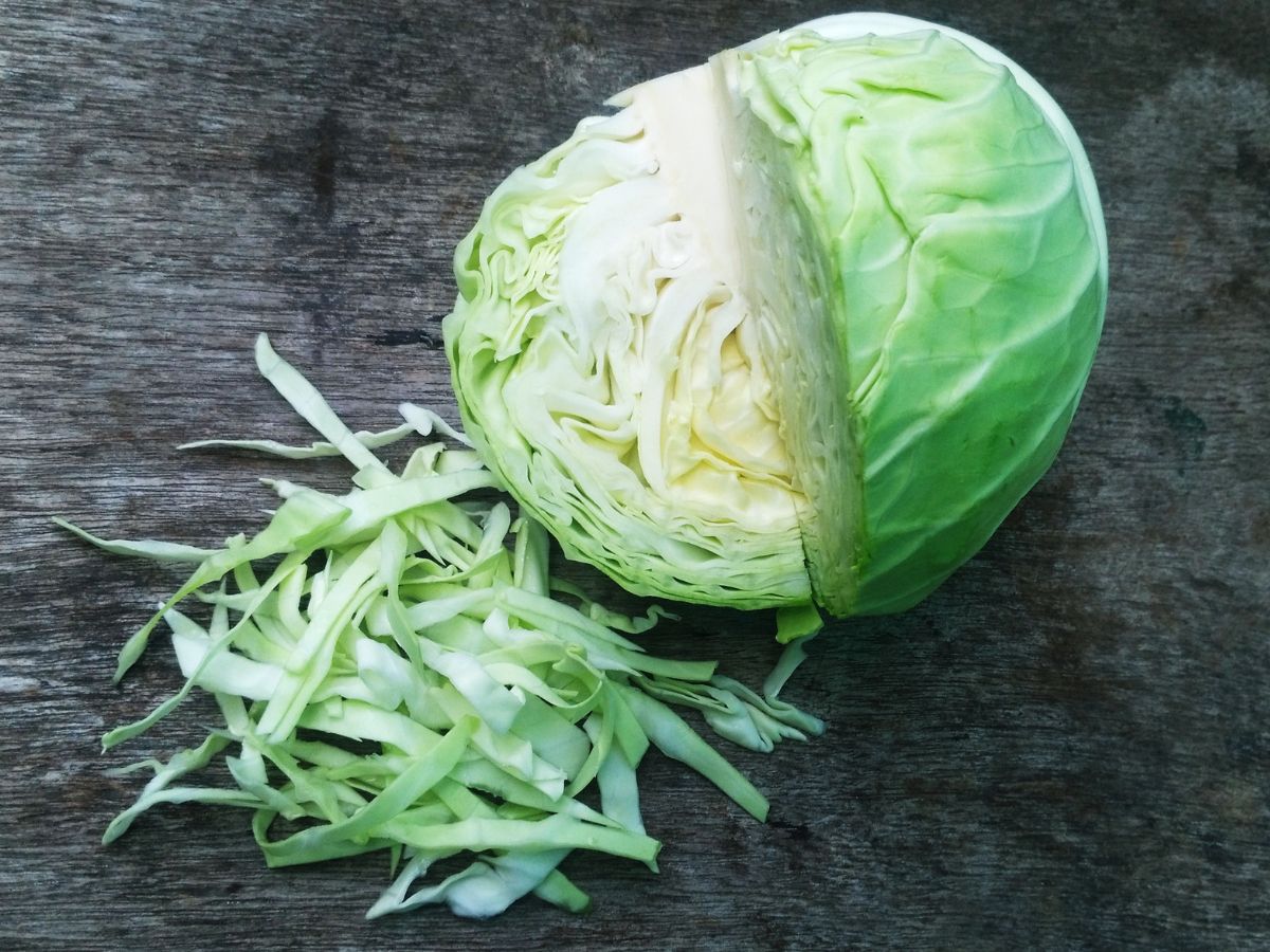 Partially sliced green cabbage on a table.