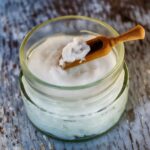 Glass jar of coconut oil with a wooden spatula.