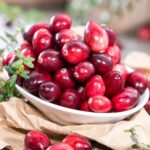 A small white bowl full of ripe cranberries.