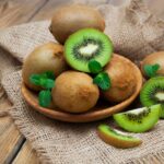 Ripe fresh organic kiwi fruits on a wooden plate.