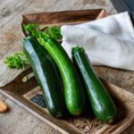 Fresh organic zucchini on a wooden plate on a wooden table.