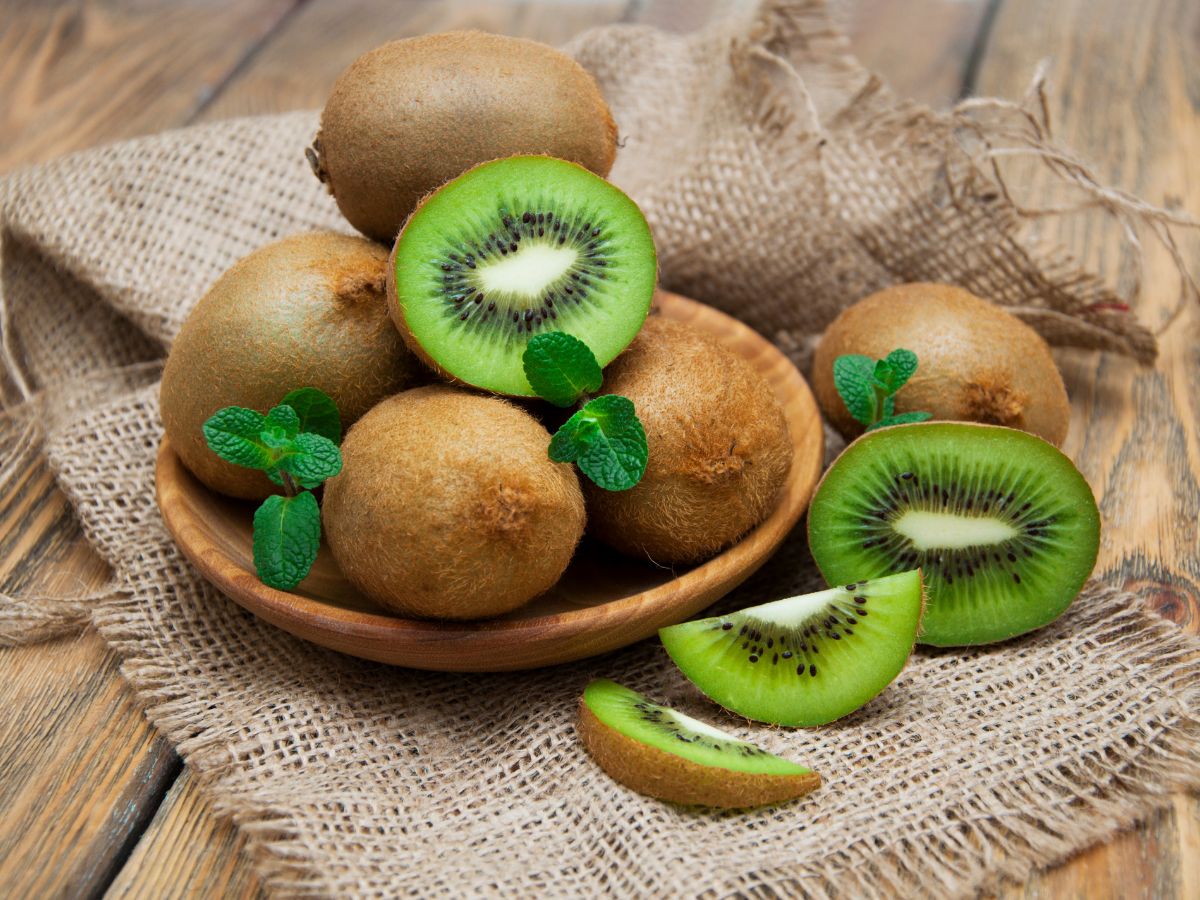 A wooden plate of fresh organic kiwi fruits on a wooden table.