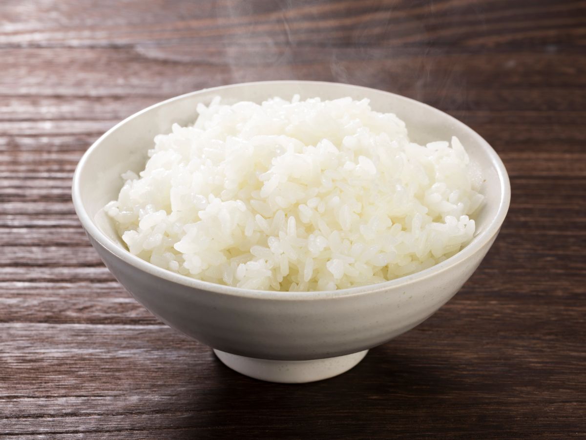 A bowl of steaming white rice on a table.