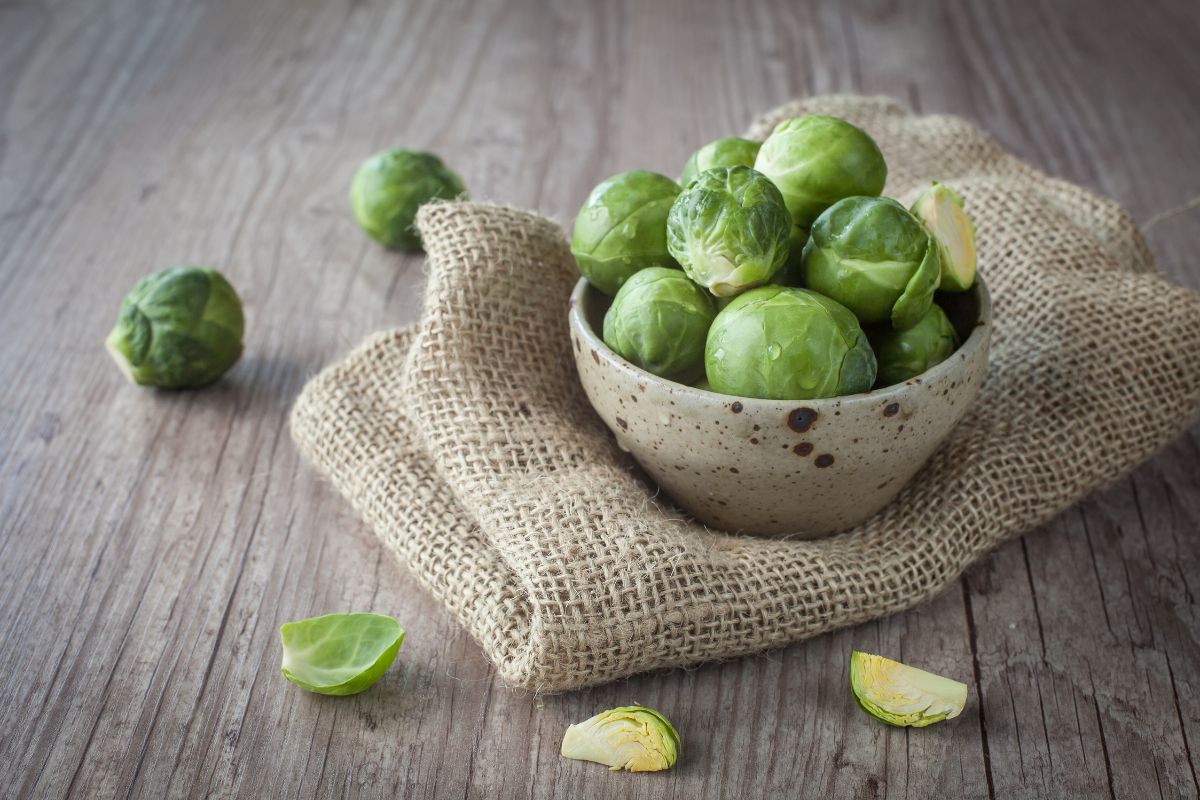 A bowl of organic Brussel sprouts on a wooden table.