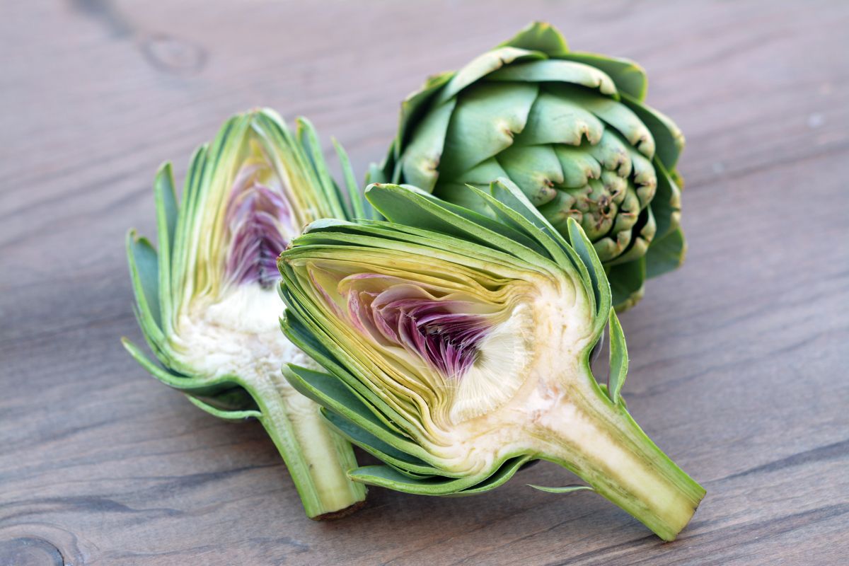 Whole and sliced artichoke on a table.