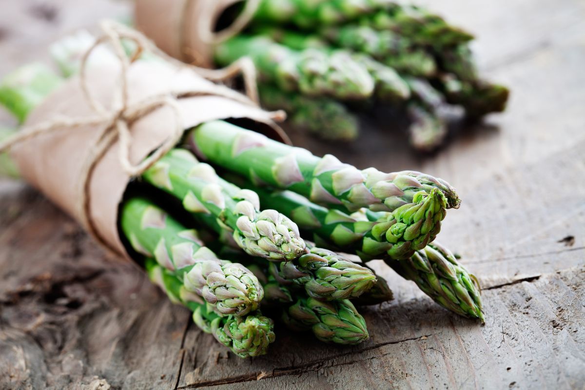Two packets of organic asparagus on a wooden table.