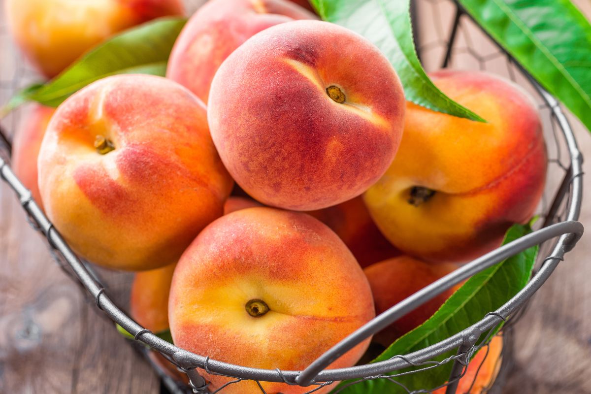 A basket full of organic ripe peaches on a table.