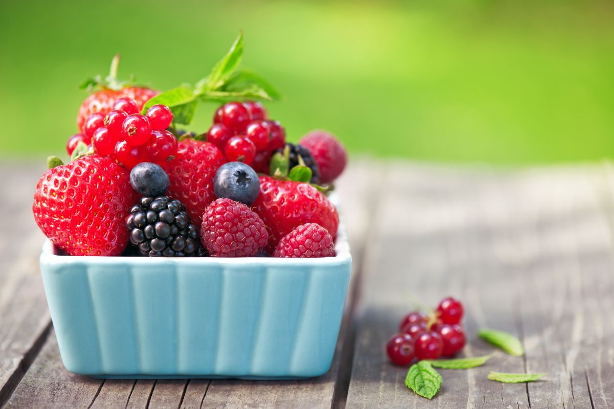 A blue bowl full of ripe berries on a wooden table.