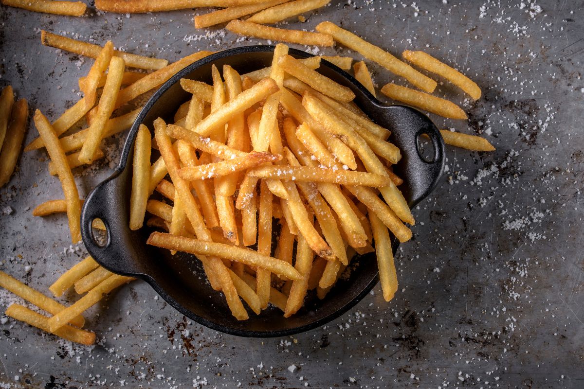 French fries in a black bowl and on a table.