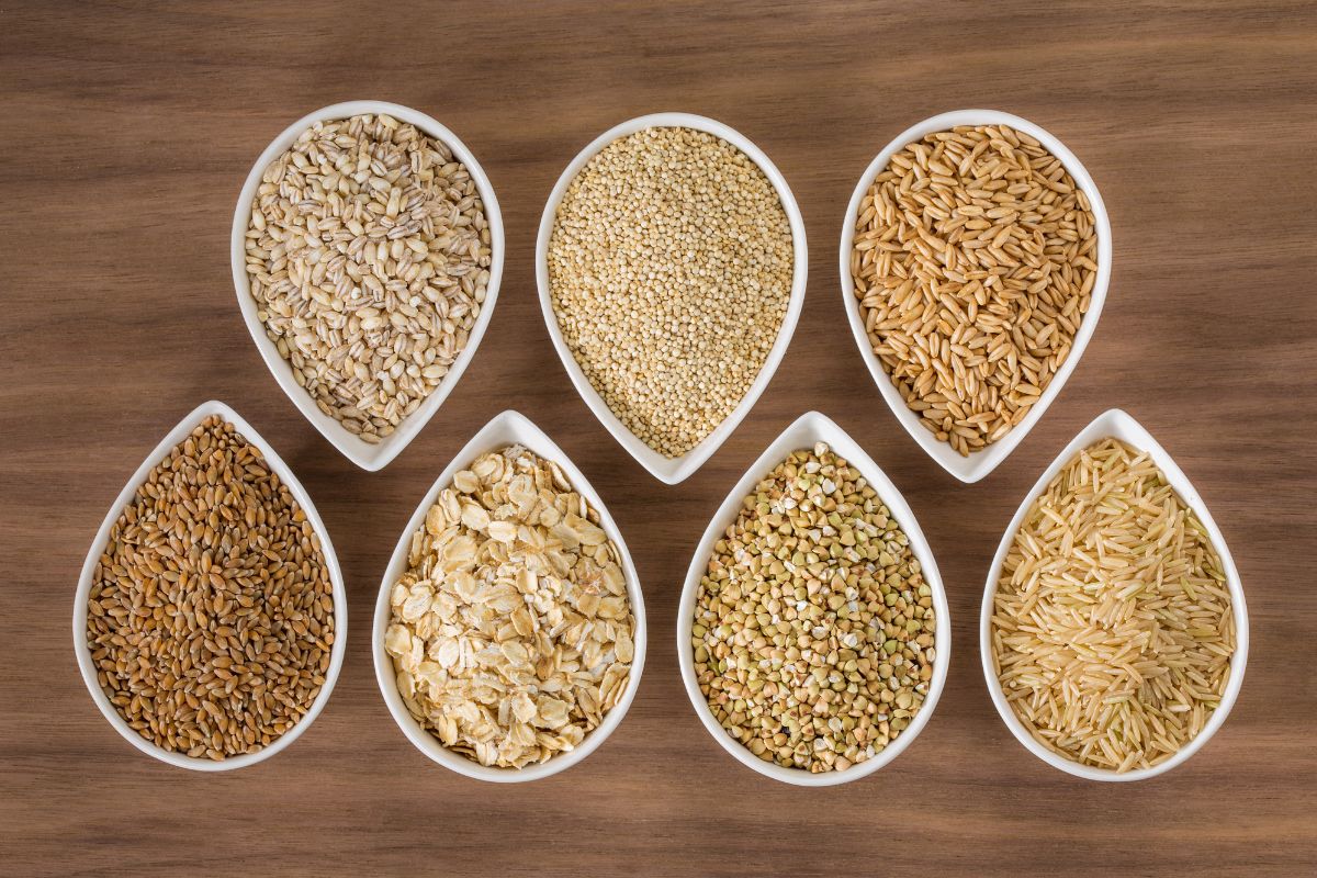 7 bowls of different varieties of grain on a table.