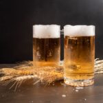 Two glasses of beer on a table.