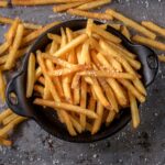 A black bowl full of french fries.