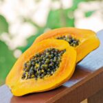 Two halves of papaya on a wooden railing.