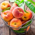 A basket full of ripe organic peaches on a table.