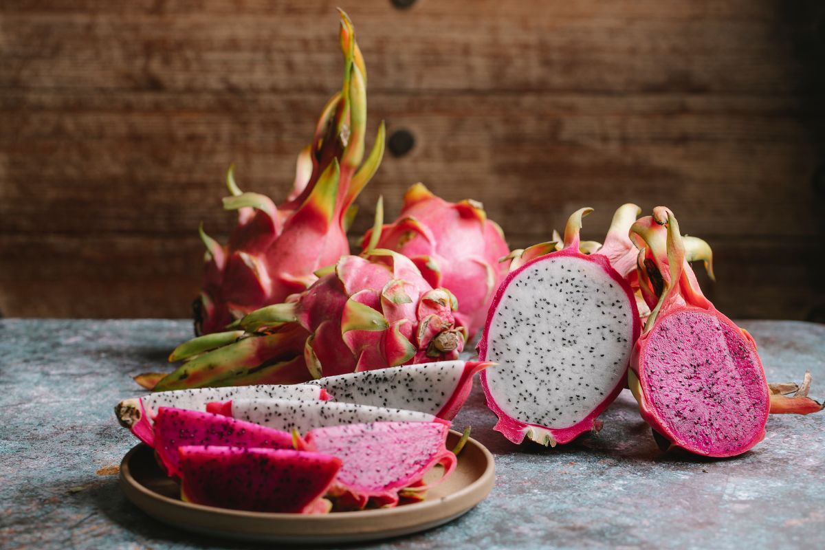 Whole and sliced dragon fruits on a table.