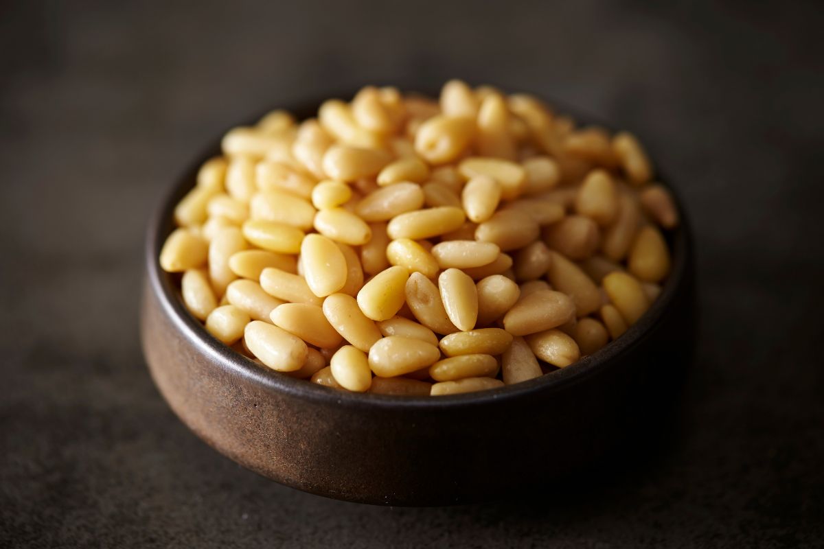 A wooden bowl full of pine nuts.