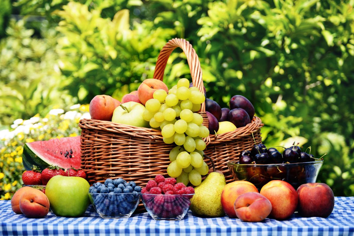 Different varieties of ripe fruits in a basket and on a table.