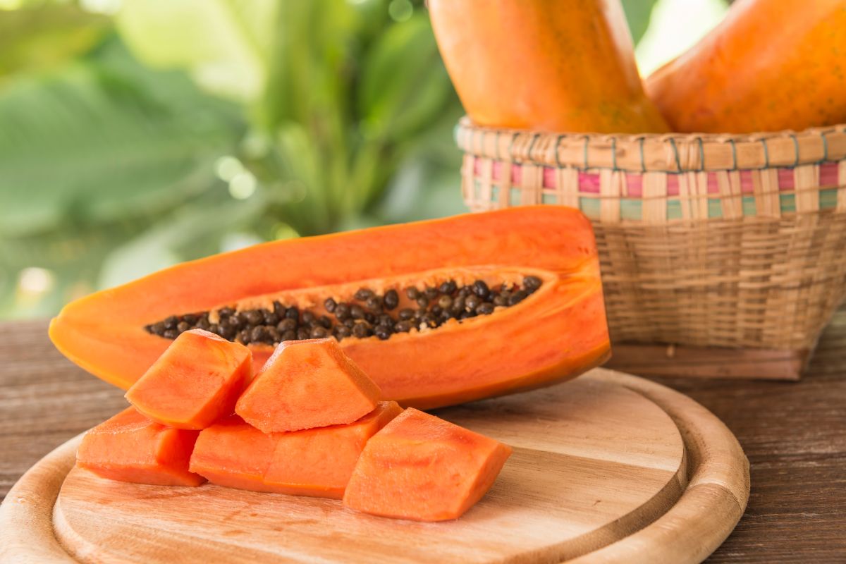 Sliced papaya on a wooden cutting board on a wooden table.