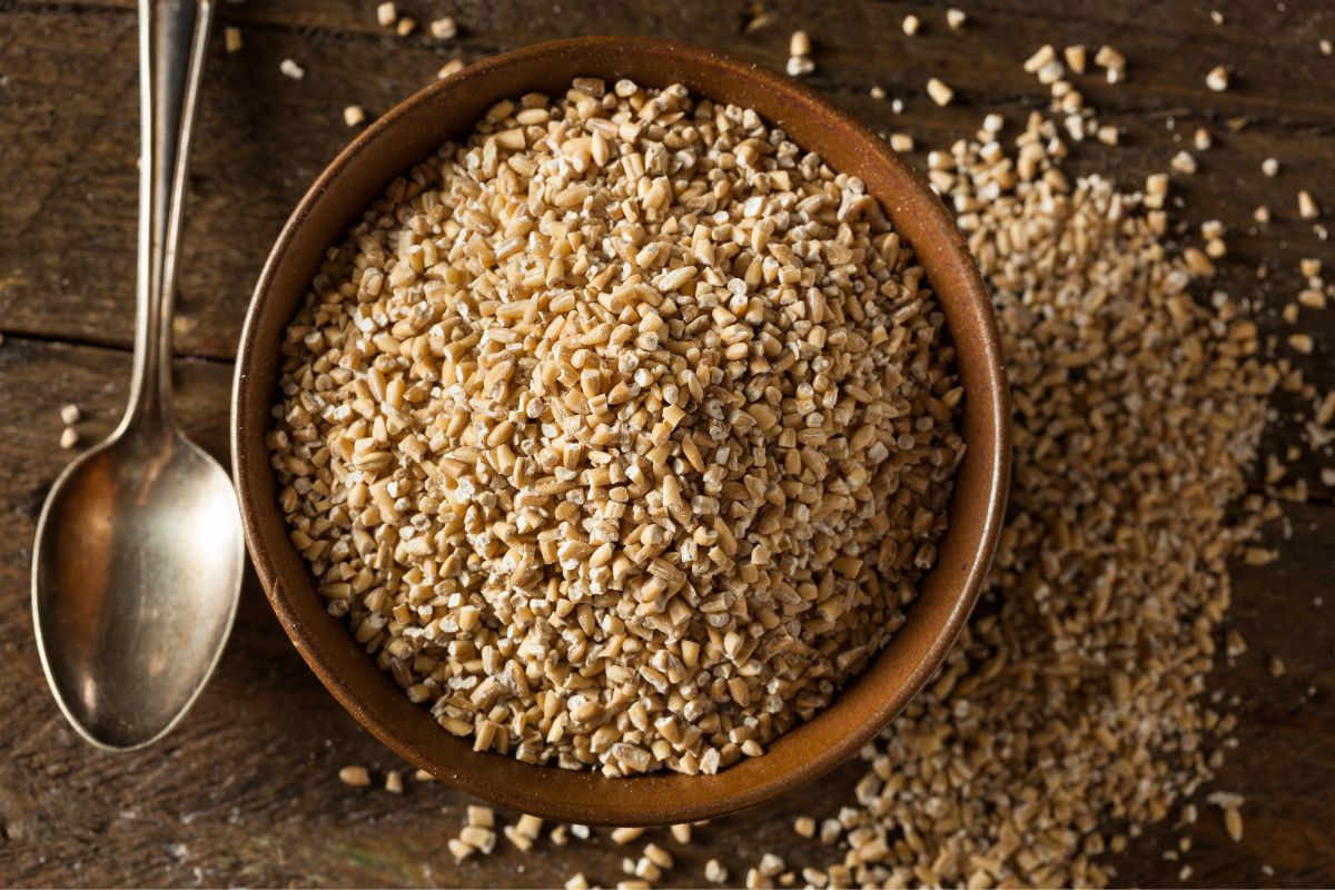 A bowl full of steel cut oats on a wooden table with a spoon.