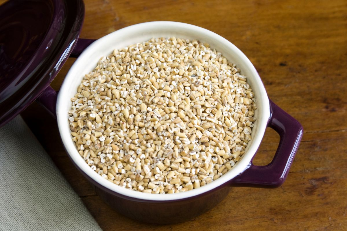 A brown pot full of steel cut oats on a table.