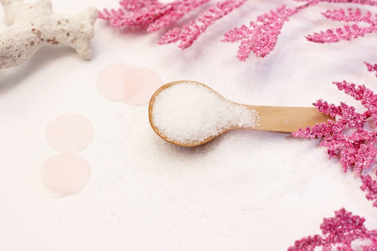 Epsom salt on a wooden spoon on a pile of Epsom salt.