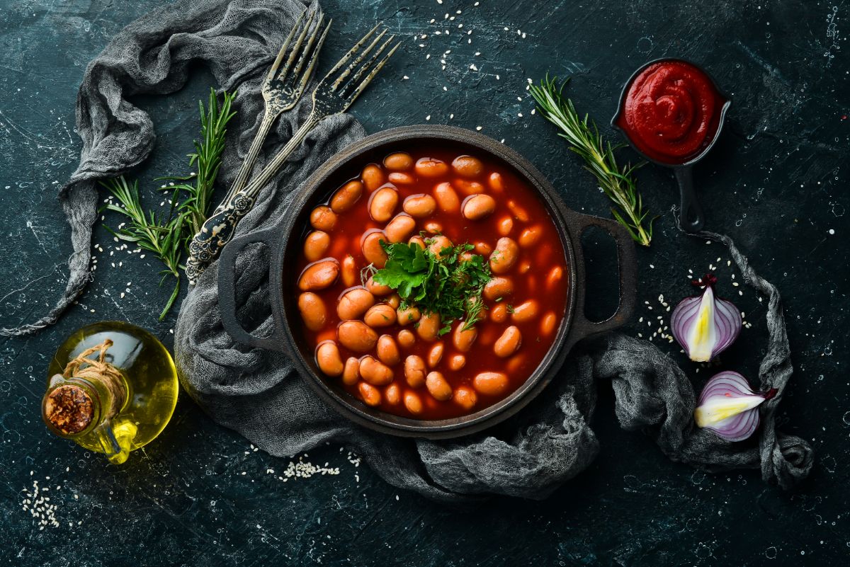 Bowl of baked beans on a table with ingredients aounrd.