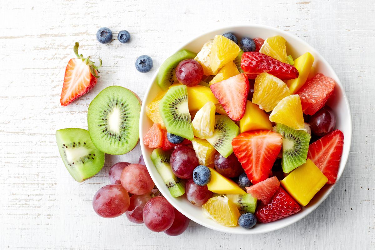 Different varieties of sliced fruits on a plate and on a table.