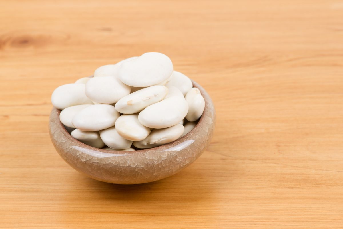 A tiny bowl full of lima beans on a table.