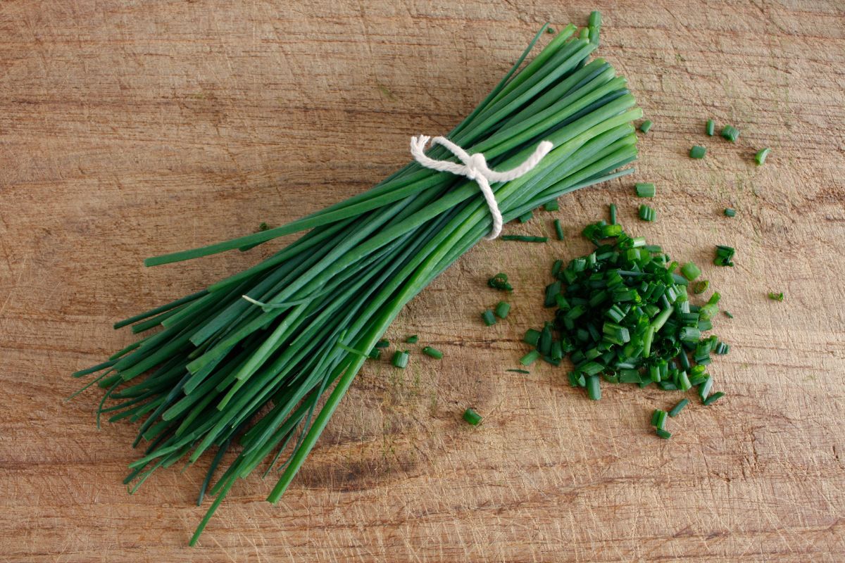 A pack of fresh chives on a wooden table.