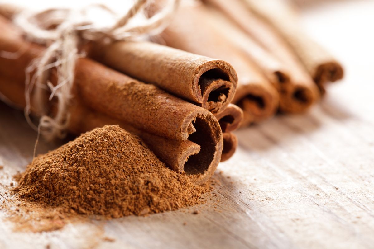 Cinnamon dust and cinnamon rolls on a wooden table.