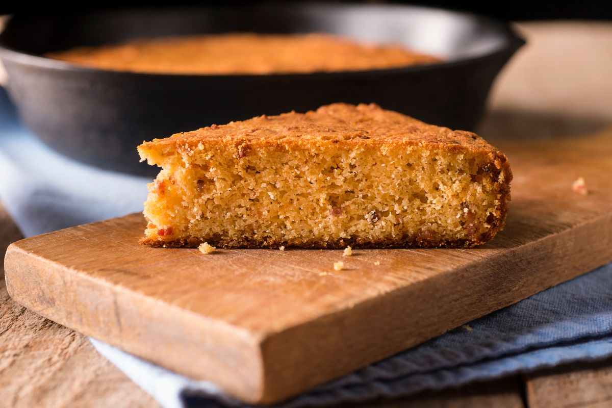 A freshly baked piece of cornbread on a wooden cutting board.
