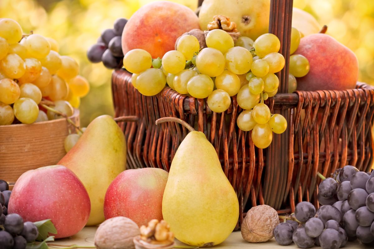 Different varieties of ripe fruits in a basket and on a table.