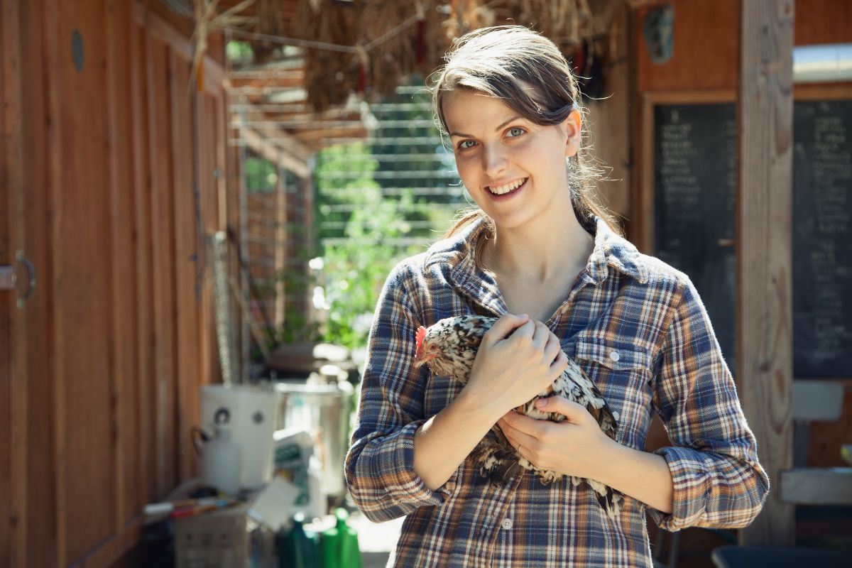 A young woman holding a chicken.