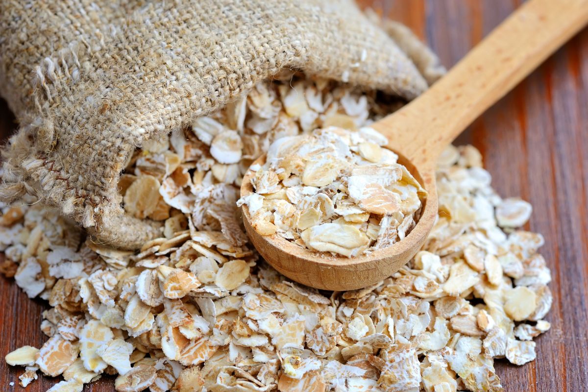 A sack of oats spilled on a table with a wooden spoon.