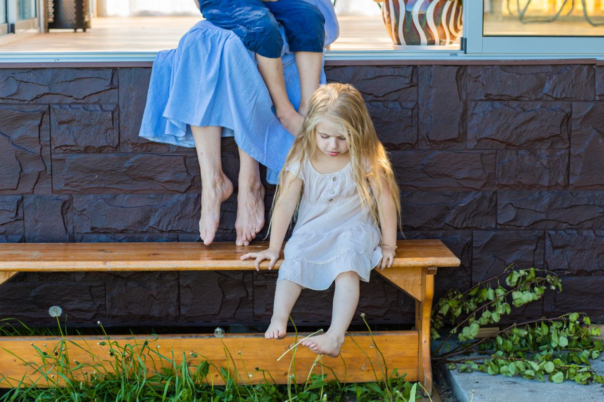 Little girl sitting on a wooden bench and grieving.