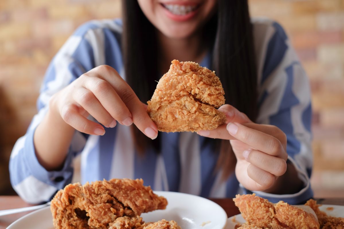 Young woman holding a fried chicken.