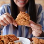 Young woman holding a fried chicken.